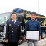 初期消火に貢献し、感謝状が贈られた中島昴さん（右）と、消火に使ったコンクリートポンプ車＝三木市福井、三木市消防本部