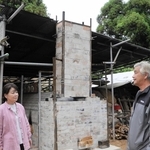 森林に囲まれた土地に再建した窯を見守る坂口忠則さん（右）＝神戸市西区神出町北