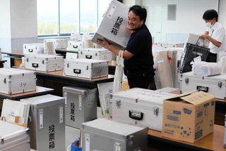 投票所ごとに仕分けられた投票箱などを運び出す市職員＝三木市役所