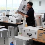 投票所ごとに仕分けられた投票箱などを運び出す市職員＝三木市役所