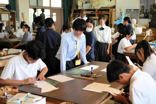美術の体験授業でペーパークラフトに挑戦する中学生を見守る高校生（中央）＝三木市別所町小林
