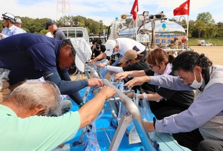 給水車からの水を専用の袋に入れる実際の動きを学ぶ参加者ら＝三木山総合公園