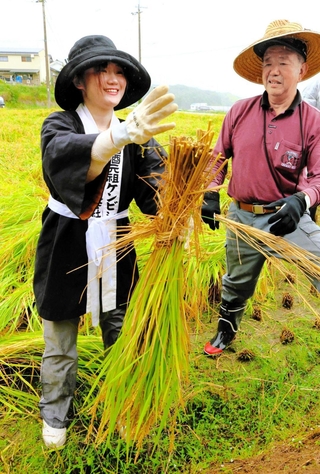 山田錦の稲刈り作業に挑戦した大学生（左）と指導役の阪本昭村米部会長＝三木市吉川町冨岡