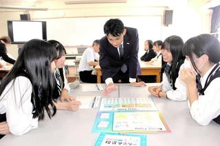 メットライフ生命保険の社員（中央）に教わりながら投資を学ぶゲームを楽しむ生徒＝三木東高校