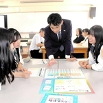 メットライフ生命保険の社員（中央）に教わりながら投資を学ぶゲームを楽しむ生徒＝三木東高校