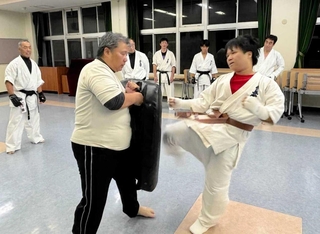 昇段審査の組手で、最後に近野凌太朗さん（手前右）の蹴りを受ける父一弘さん＝三木市立総合隣保館