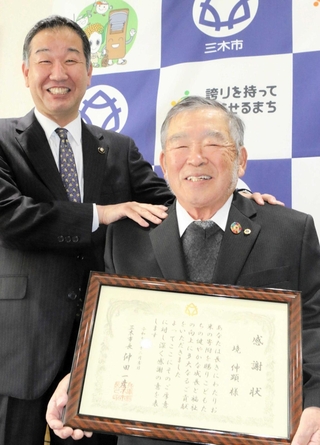 仲田一彦市長（左）から感謝状を受け取った境伸顕さん＝三木市役所