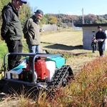 リモート操縦できる草刈り機のデモンストレーションを見学する住民ら＝三木市吉川町上中