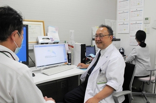 診療室で職員と話す認知症診療センター長の濱口浩敏。笑顔が相手の心をほぐす＝北播磨総合医療センター