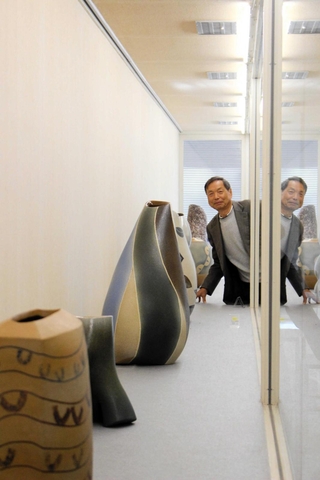 藤原義明さん（奥）の４６年に及ぶ作陶の成果が並ぶ会場＝堀光美術館