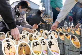 絆や希望などの祈りが書き込まれた竹灯籠に明かりをともす参加者＝三木市末広１