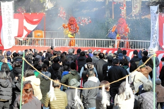 桜に見立てた枝を持って舞台に上がった鬼を見守る参拝客＝大宮八幡宮