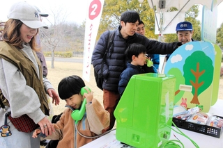 クイズラリーの道中で災害用伝言ダイヤルの仕組みを学ぶ親子ら＝県立三木総合防災公園