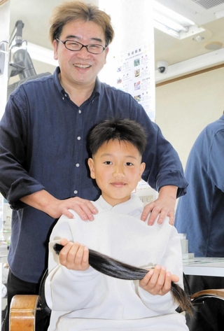 切ってもらった髪を手に、晴れやかな笑顔を見せる小紫心瑛さん＝三木市福井１