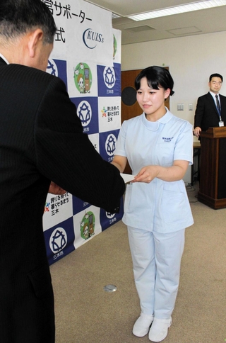 仲田一彦市長（左）から委嘱状を受け取る看護学科４年の今村心愛さん＝関西国際大学三木キャンパス