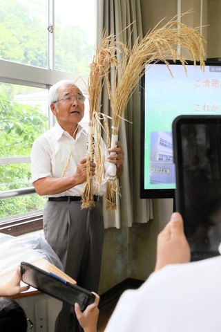 吉川町の村米制度や山田錦の特徴について稲穂を手に語る矢野義昭さん＝吉川中学校