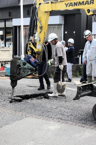 陥没でできた穴を掘り、原因を調べる作業員ら＝三木市府内町