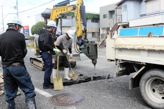 陥没でできた穴を掘り、原因を調べる作業員ら＝三木市府内町