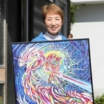 色鮮やかな花が咲く自宅前で出展作を手にする玉富眞弓さん＝三木市本町３