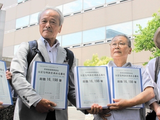 集めた署名を手にする菅野みずえさん（右）と夫の昭雄さん＝大阪市北区