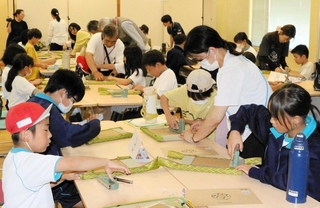 イグサの香りに包まれてミニ畳作りに挑戦する小中学生＝三木市吉川町吉安