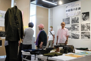 市民から寄せられた戦時中の国民服（左）や飯ごうなどを見つめる来場者＝みっきぃホール
