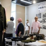 市民から寄せられた戦時中の国民服（左）や飯ごうなどを見つめる来場者＝みっきぃホール