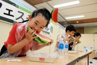 スイカの早食い競争でかぶりつく子どもら＝道の駅よかわ