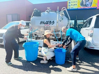 片岡憲彦さんの給水車から水をくむ地元住民ら＝熊本県氷川町（片岡さん提供）