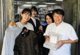 播州織の製品を手にする小林郁香さん（左端）と高橋欣也さん（右端）＝小円織物