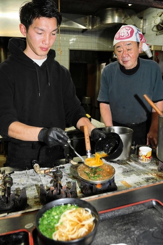 楞野正之さん（右）が見守る中、看板メニューのカツ丼を仕上げる西村洋祐さん＝いずれも神戸市兵庫区永沢町２