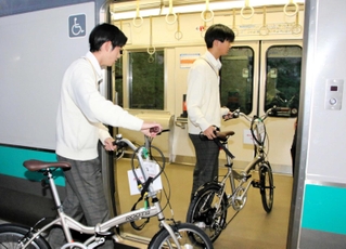 サイクルトレインの実証実験でＪＲ加古川線の車両に自転車を押して乗り込む高校生＝ＪＲ新西脇駅