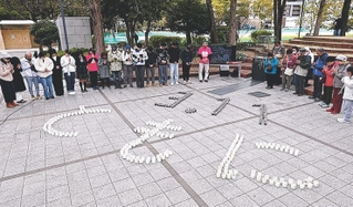 東日本大震災の発生時刻に合わせ、神戸で開かれた追悼行事。ろうそくで「３．１１　ともに」の文字を書いた＝１１日午後２時４６分、神戸市中央区加納町６（撮影・小林良多）