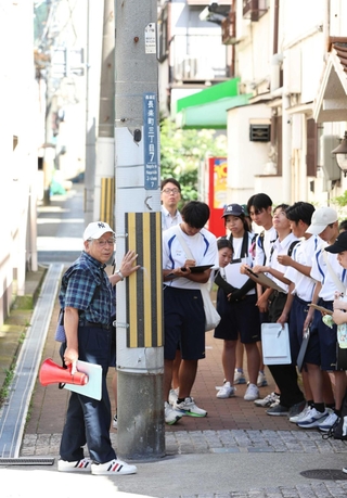 震災前から立つ路地の電柱を見学する舞子高校の生徒ら＝神戸市長田区長楽町３