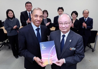 ＷＨＯ神戸センターが閉所に合わせて制作した記念誌を手にする同センターのロイック・ギャルソンさん（手前左）と兵庫県の山下輝夫保健医療部長（同右）＝兵庫県庁（撮影・鈴木雅之）