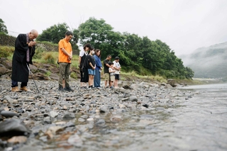 ２０２０年７月の豪雨から６年となり、氾濫で多くの被害をもたらした球磨川に向かい黙とうする人たち＝４日午前、熊本県八代市