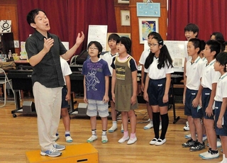 西灘小学校の児童に歌唱指導をする臼井真さん（左端）＝２０１４年１０月、神戸市灘区船寺通３