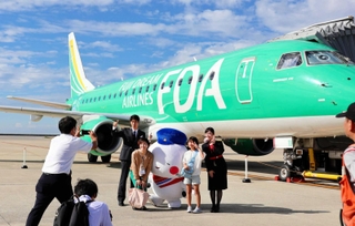 搭乗前、機体をバックに記念撮影する参加者ら＝神戸空港