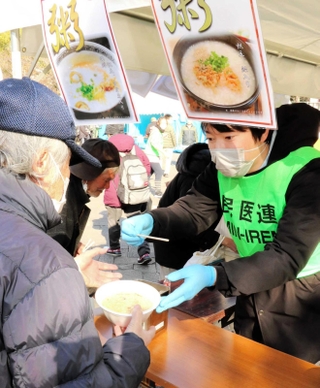 支援者から海鮮がゆを受け取る生活困窮者ら＝中央区加納町６