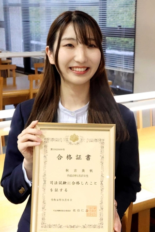 授業の空きこまに司法試験の勉強をしていた関学大の図書館で合格証書を持つ秋吉美帆さん＝西宮市上ケ原一番町