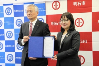 協定書を手にする丸谷聡子市長（右）と高坂誠学長＝明石市役所