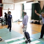 明石署員の補助を受けながら模擬道路の交差点を手を上げて渡る生徒＝明石市大久保町大窪