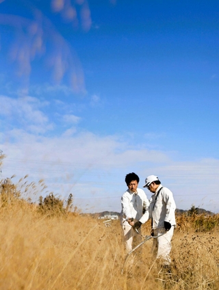 宿泊体験者（右）に草刈り機の使い方を伝える西岡晋矢さん＝いずれも三木市久留美