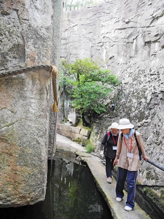 生石神社の巨石「石の宝殿」を見学するクリエイティブタウンゼミのゼミ生ら＝高砂市阿弥陀町生石