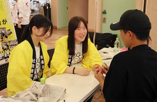 来場者に牛乳パックを使ったスプーンの作り方を教える甲南女子大の学生ら＝西宮市北口町