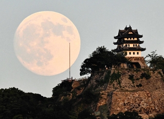 明るさの残る空に浮かぶ月と洲本城の模擬天守＝６日午後、洲本市物部１から撮影