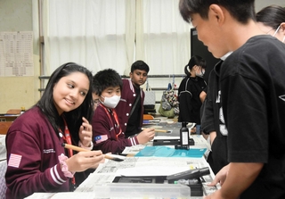 尼崎市立成徳小学校の授業に参加し、習字に挑戦するマレーシアの小学生ら＝尼崎市蓬川町