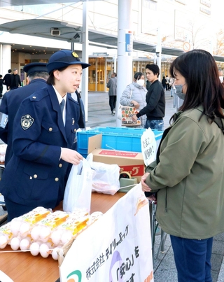 通行人らに卵などを配る明石署員（左）＝明石市大明石町１