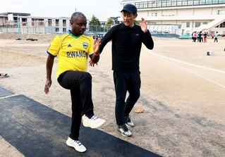 松岡紳介さん（右）から陸上のトレーニングについて教わるエマーブレ・ブレジェアさん＝明石北高校