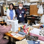 教員向け手帳カバーの縫製作業を見守る小坂尚子さん（奥左）ら＝三田市南が丘１